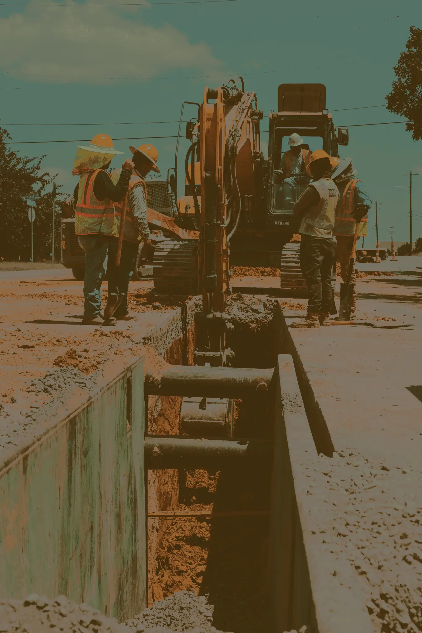 A group of construction workers observing an excavator digging a trench.